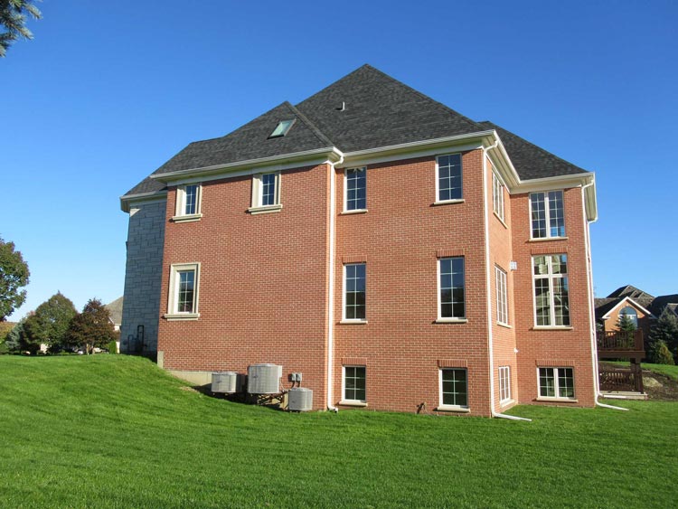 Completed dark architectural shingle roof on a brick two-story home